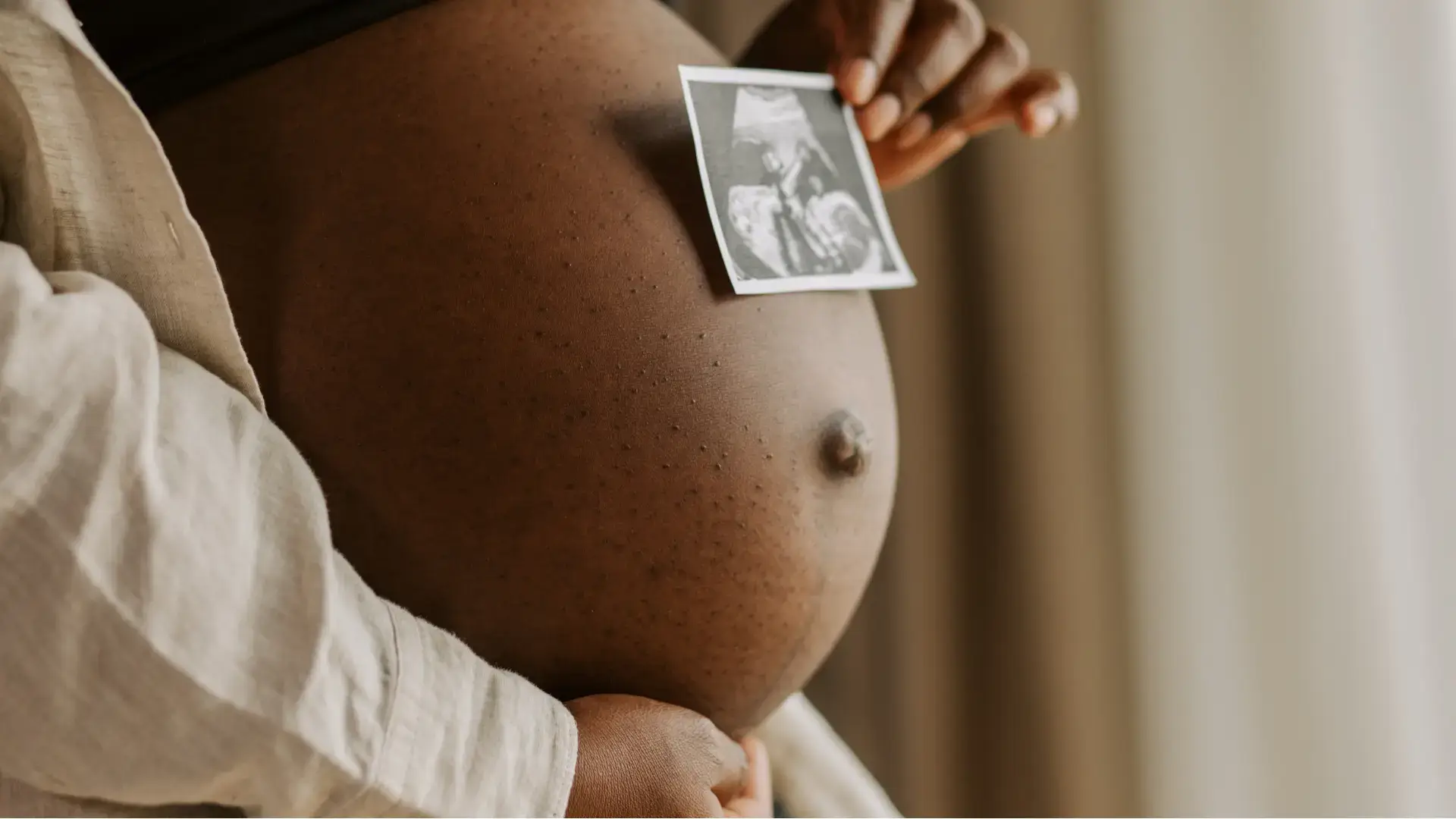 African American Pregnant Woman about to give birth, holding up a ultrasound picture of the infant baby